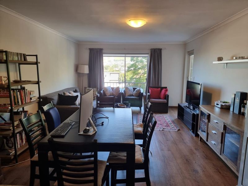 Open plan living and dining area featuring laminate flooring and a large sliding glass door leading to a balcony.