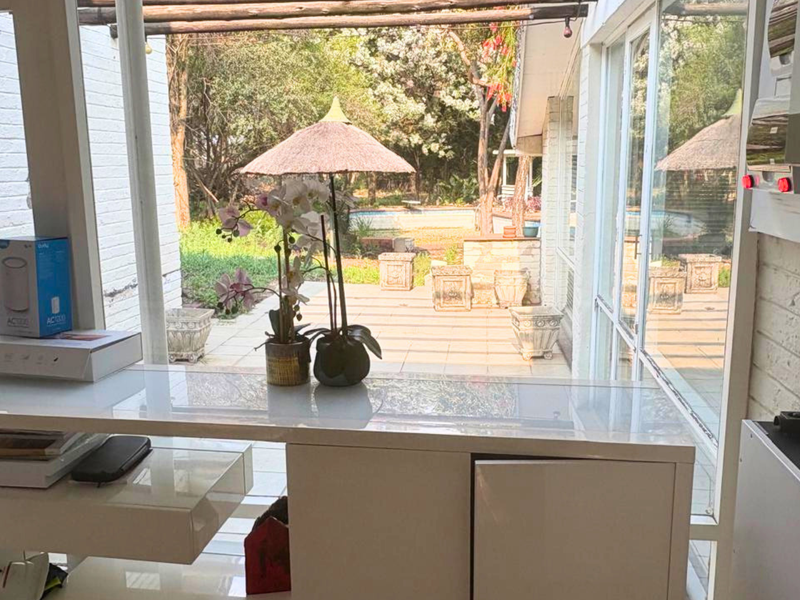 A bright sunroom or enclosed patio area featuring large sliding glass doors, a timber pergola, and integrated solar power infrastructure.
