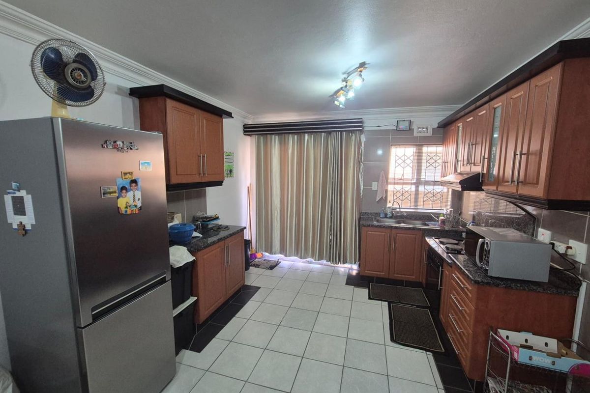 A functional kitchen featuring wood-finish cabinetry, granite countertops, tiled flooring, and a window with security bars, providing a practical workspace.