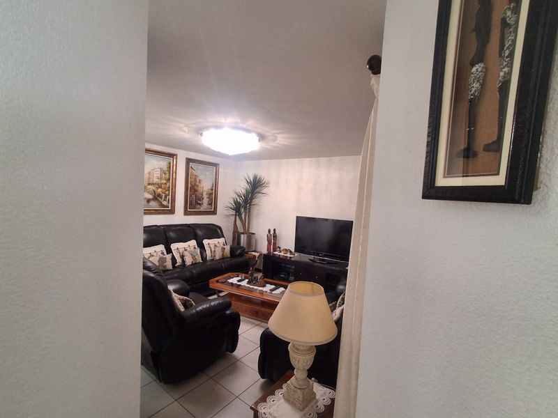 A view into a living room featuring tiled flooring and a central ceiling light fixture, viewed from an adjacent hallway.