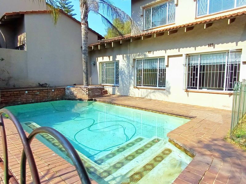 Rear exterior view of the townhouse featuring a swimming pool with brick paving and a tiled roof structure.