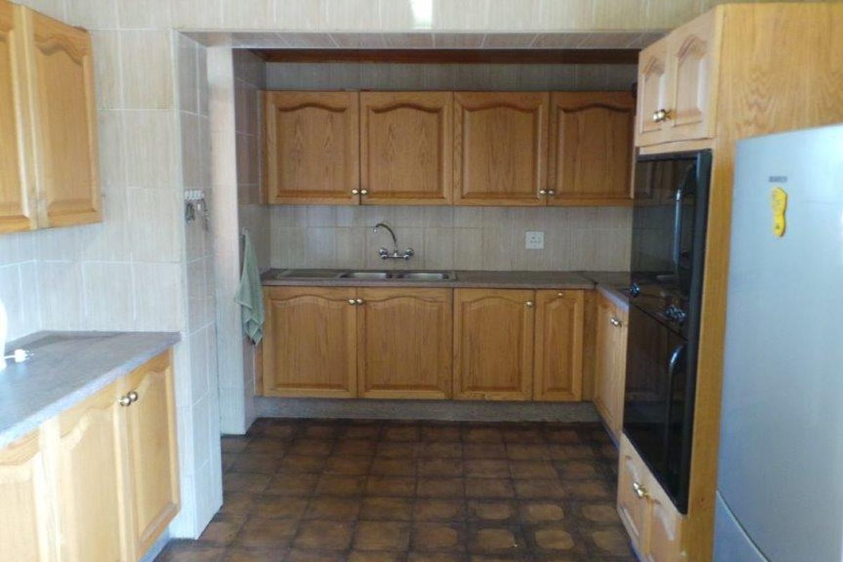 A functional kitchen featuring traditional wooden cabinetry, tiled backsplash, laminate countertops, and a built-in oven, offering a classic layout with ample storage space.