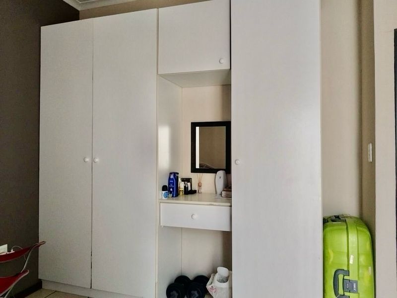 A bedroom featuring a white built-in wardrobe with an integrated vanity nook and drawer.