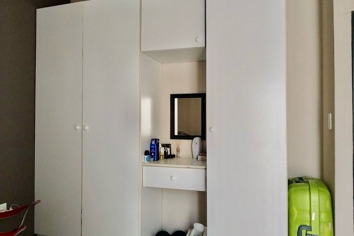 A bedroom featuring a white built-in wardrobe with an integrated vanity nook and drawer.