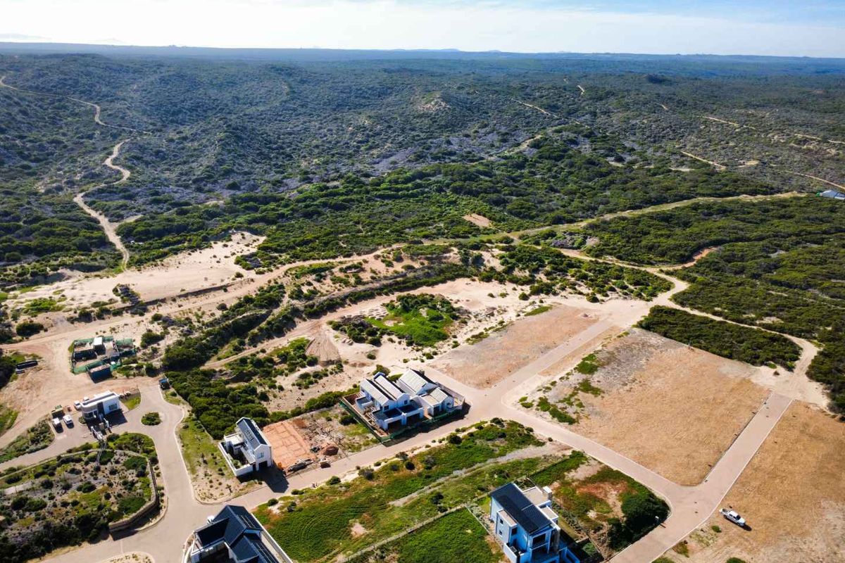 Aerial view of a residential development area featuring paved roads, established homes, and surrounding natural coastal landscape.