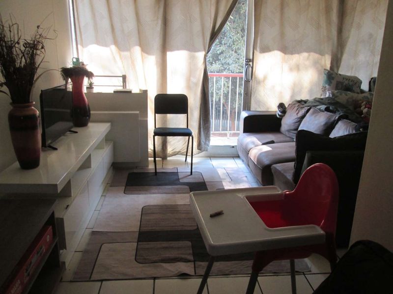 A living room area featuring tiled flooring and direct access to a balcony through a sliding glass door.