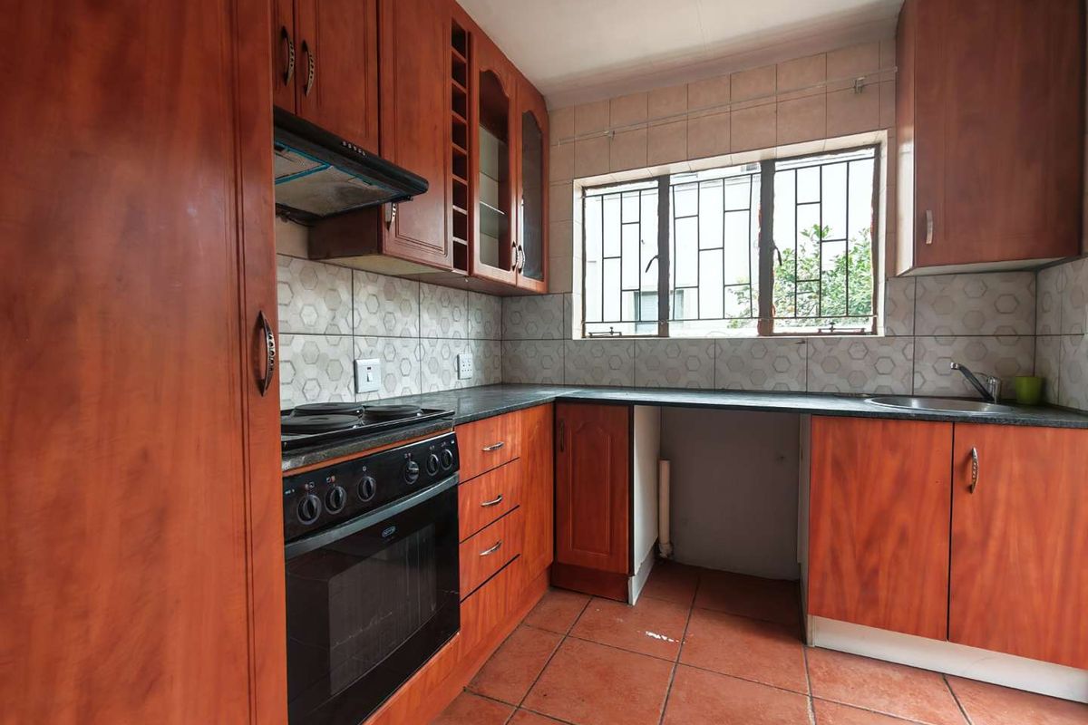 A functional kitchen featuring wood-finish cabinetry, built-in oven with extractor, tiled backsplash, and tiled flooring, offering a practical layout for renovation.