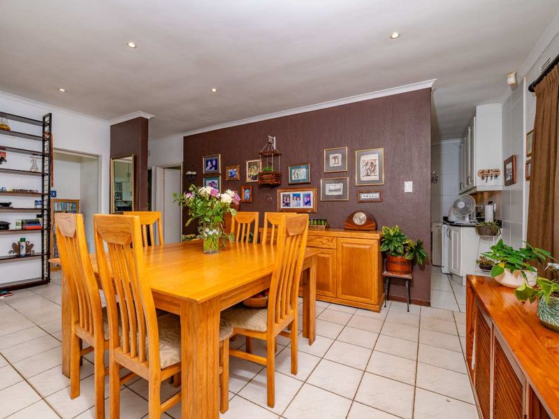 Open plan dining area featuring tiled flooring and recessed downlights, seamlessly connected to a functional kitchen space with built-in cabinetry.