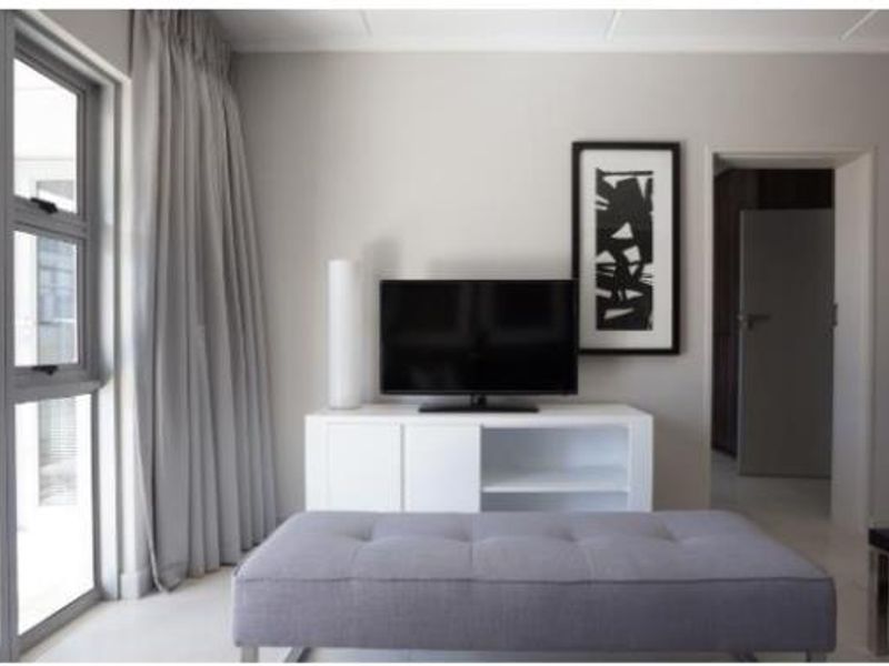 A modern living room featuring neutral wall tones, large aluminium-framed windows, and a clean, minimalist aesthetic.
