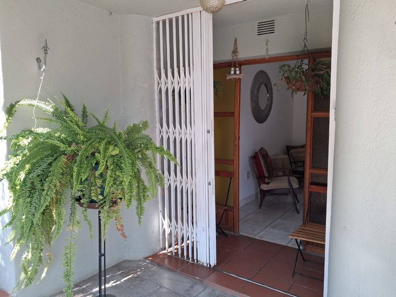 A covered patio area featuring a white security gate and tiled flooring, providing access to the interior living space.