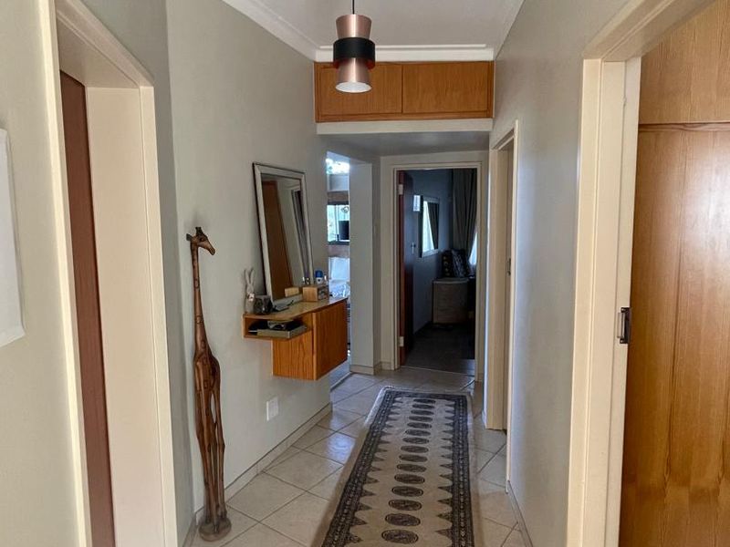 A functional hallway featuring tiled flooring, coved ceilings, and built-in storage cabinetry, providing access to multiple rooms within the home.