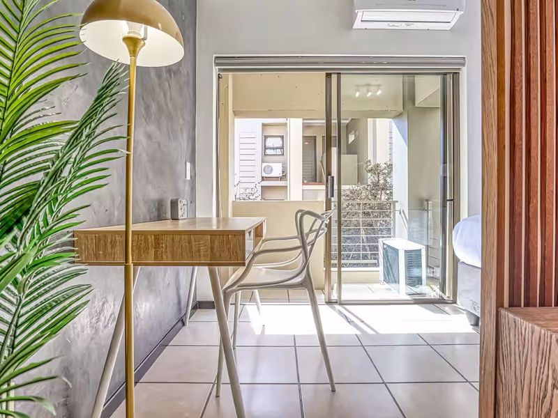 Modern bedroom featuring a textured feature wall, tiled flooring, and a sliding glass door leading to a private balcony with air conditioning.