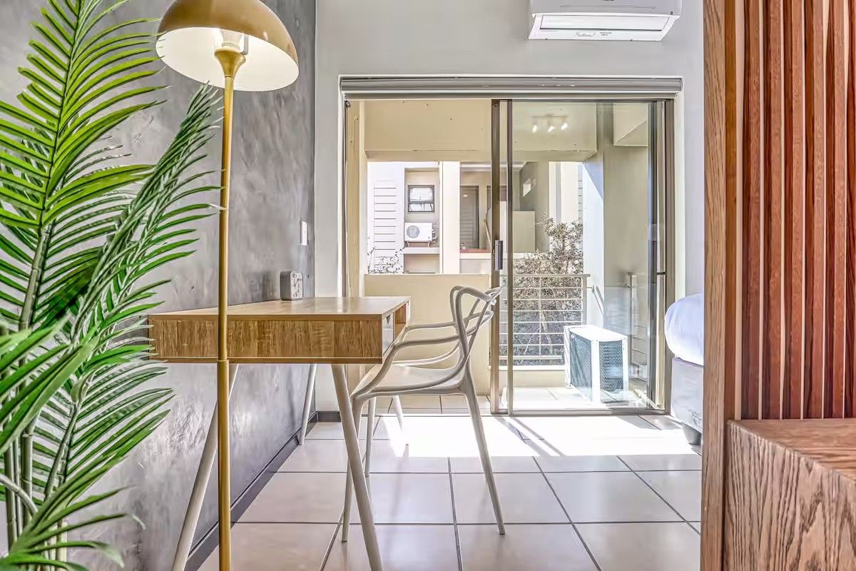 Modern bedroom featuring a textured feature wall, tiled flooring, and a sliding glass door leading to a private balcony with air conditioning.