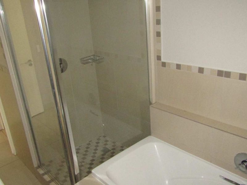 A functional bathroom featuring a separate shower enclosure and a built-in bathtub with neutral wall and floor tiling.