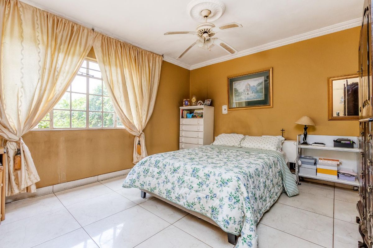 A bedroom featuring tiled flooring, a ceiling fan with decorative rose, and large window with natural light.