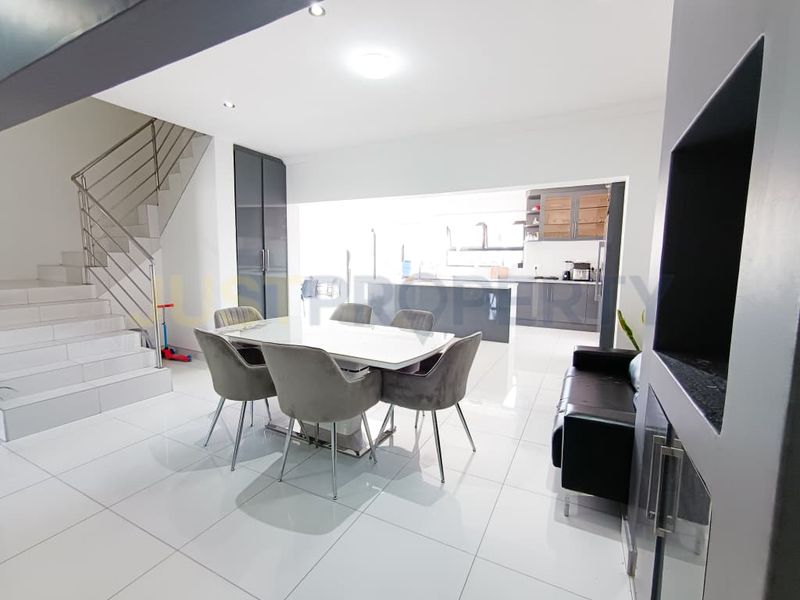 Modern open-plan living and dining area featuring sleek tiled floors, a contemporary staircase, and a seamless transition into the kitchen space.