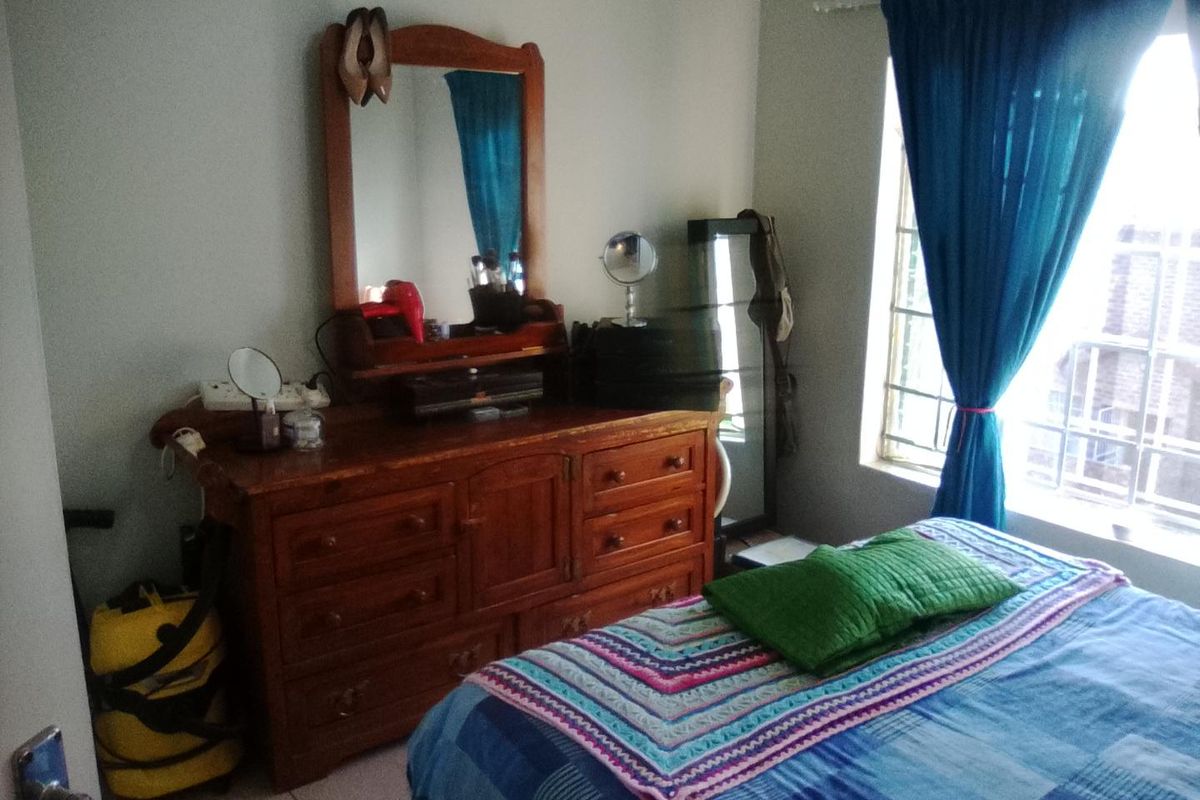 A bedroom featuring tiled flooring and a window fitted with security bars, providing natural light to the space.