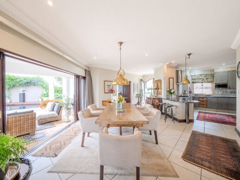 Spacious open-plan living and dining area featuring tiled floors, recessed lighting, and seamless flow to the outdoor patio through large sliding glass doors.