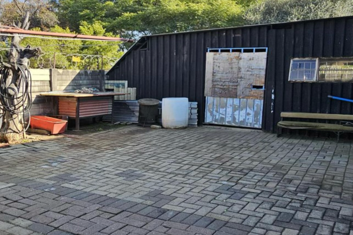Rear courtyard area featuring paved flooring, timber-clad structure, and secure boundary walling, requiring maintenance and cosmetic updates.