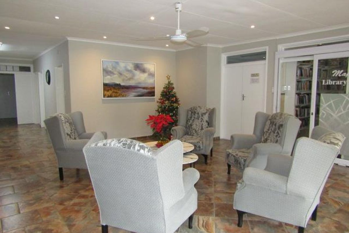 A communal lounge area within the retirement village, featuring tiled flooring, recessed ceiling lighting, and a ceiling fan.