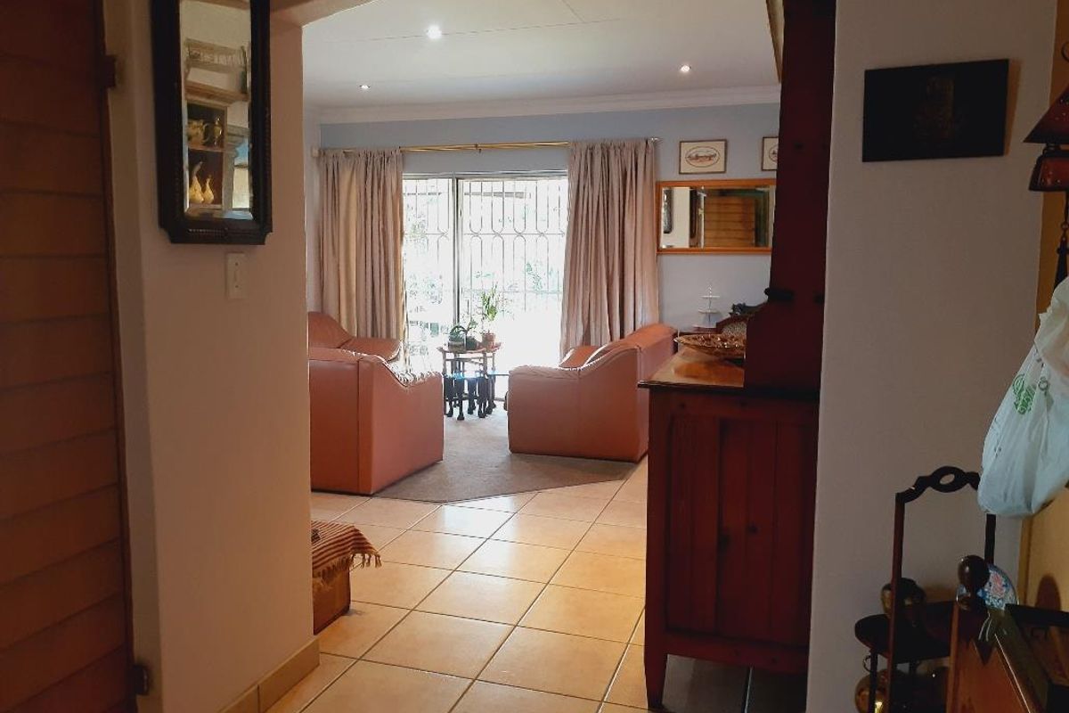 View from a hallway looking into a living room with tiled flooring and sliding glass doors leading to an outdoor area.