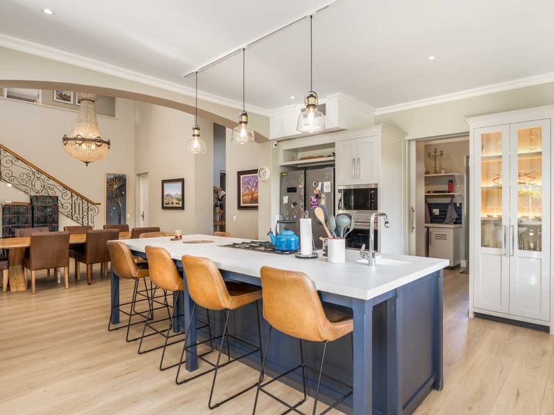 Spacious open-plan kitchen featuring a large central island, modern cabinetry, integrated appliances, and a seamless transition to the dining area and staircase.