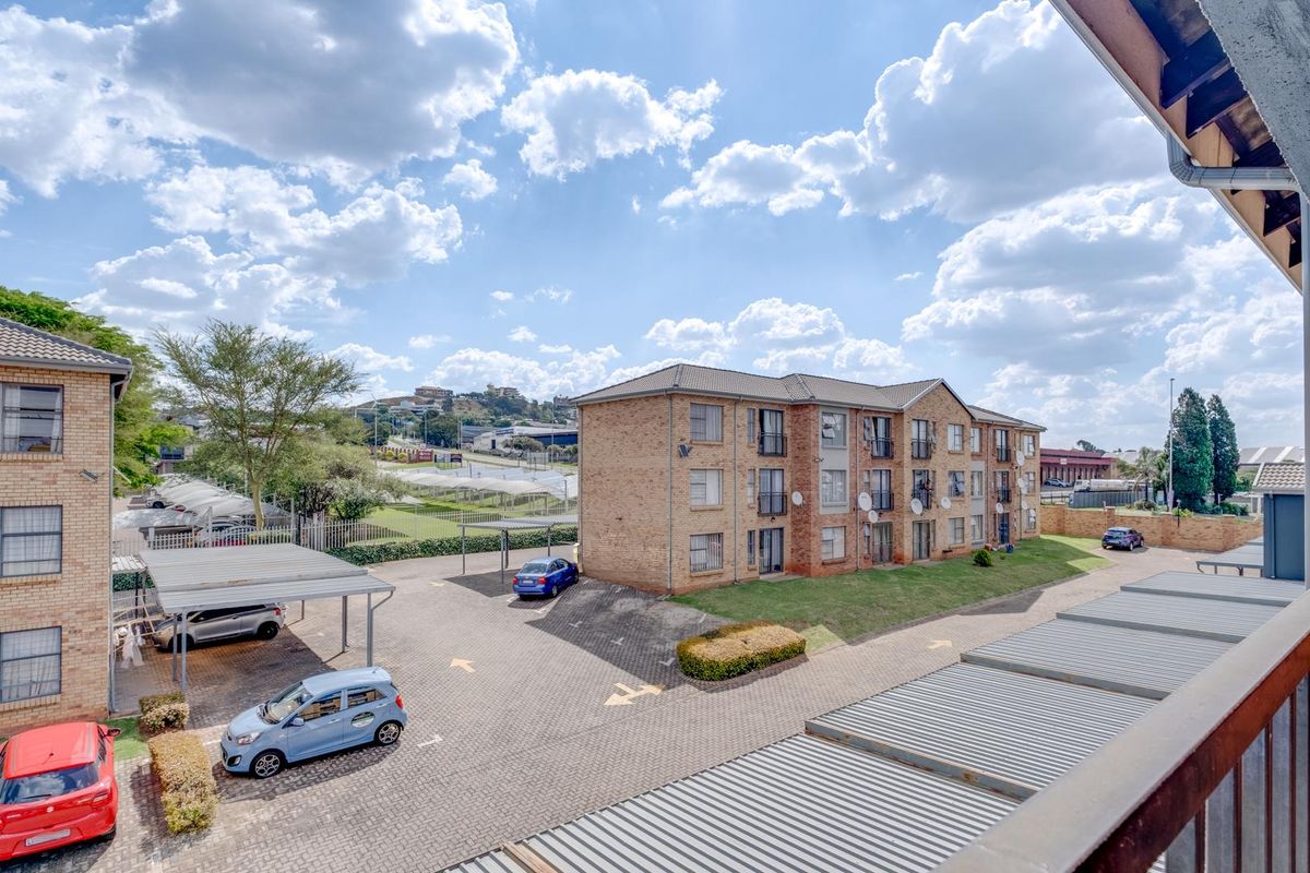 Elevated view of an apartment complex exterior featuring brick facades, paved parking areas with carports, and landscaped grounds.