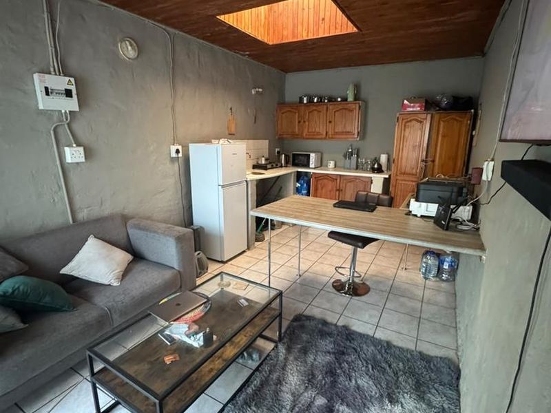 Open-plan living and kitchen area featuring a timber ceiling with a skylight, tiled flooring, and basic cabinetry.