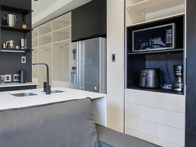 Modern open-plan kitchen area featuring sleek built-in cabinetry, a central island with a double sink, and integrated appliances.