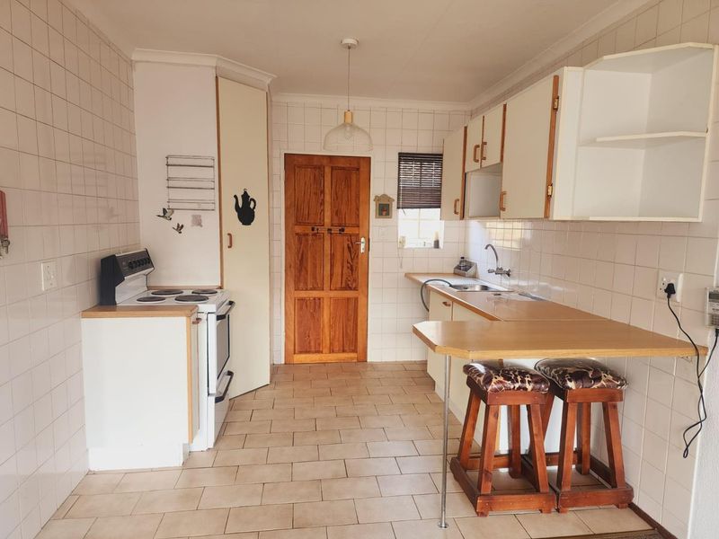 A functional kitchen featuring tiled walls and flooring, built-in cabinetry, a breakfast counter, and a freestanding stove.