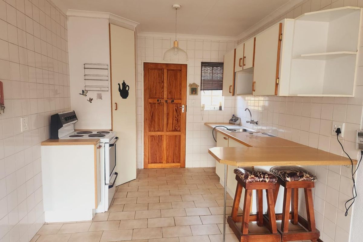A functional kitchen featuring tiled walls and flooring, built-in cabinetry, a breakfast counter, and a freestanding stove.