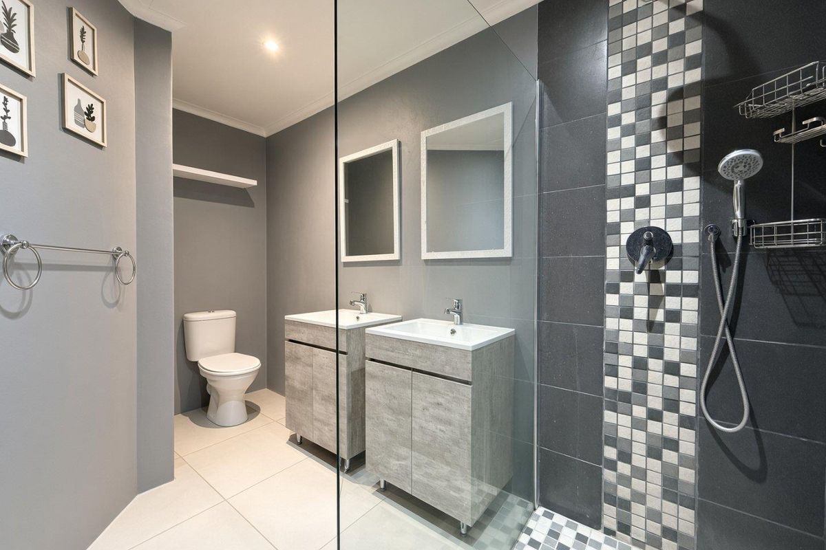 Modern bathroom featuring a dual vanity, walk-in shower with mosaic tile accents, and contemporary grey finishes.