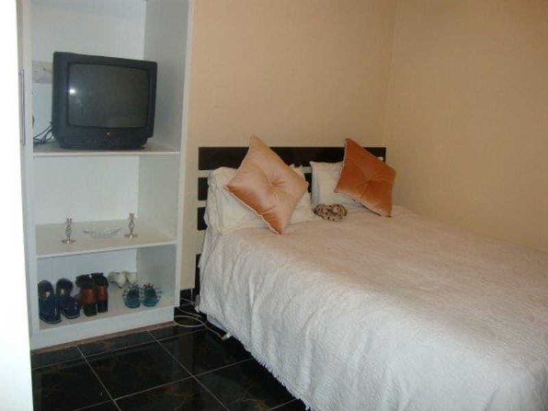 A bedroom featuring dark tiled flooring and a built-in white shelving unit for storage.