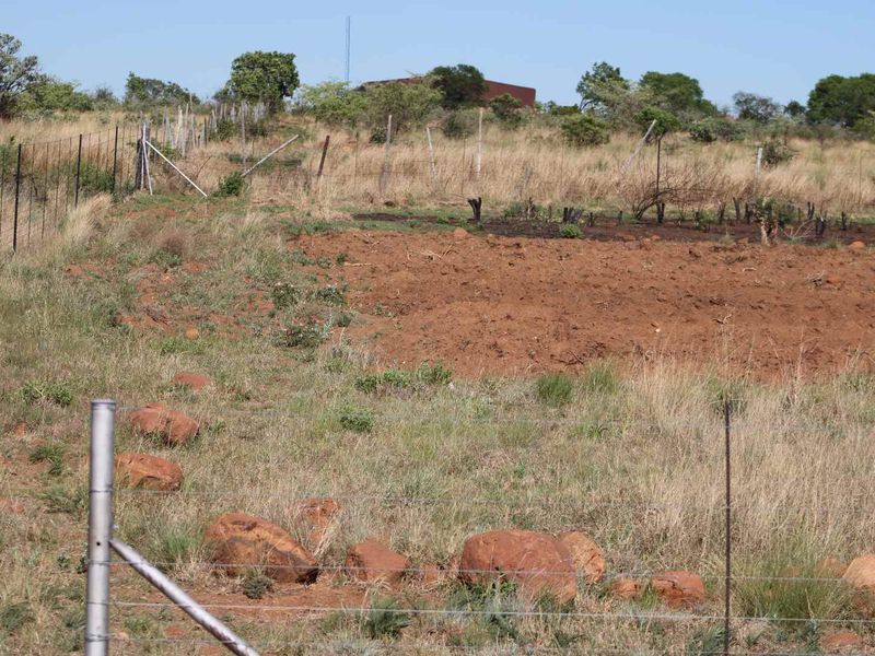 An undeveloped plot of land on a small holding featuring wire fencing and natural terrain with visible soil erosion.