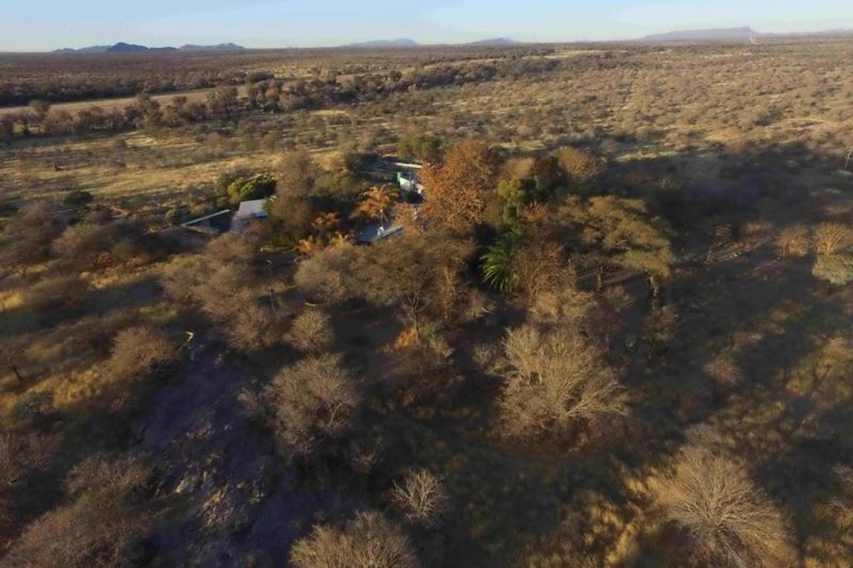 Aerial view of the small holding property, showcasing the expansive landscape, natural vegetation, and the main dwelling nestled within the trees.