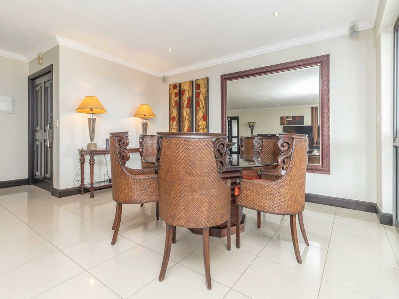 A bright dining room featuring polished tiled flooring, recessed downlighting, and a large sliding glass door providing natural light.