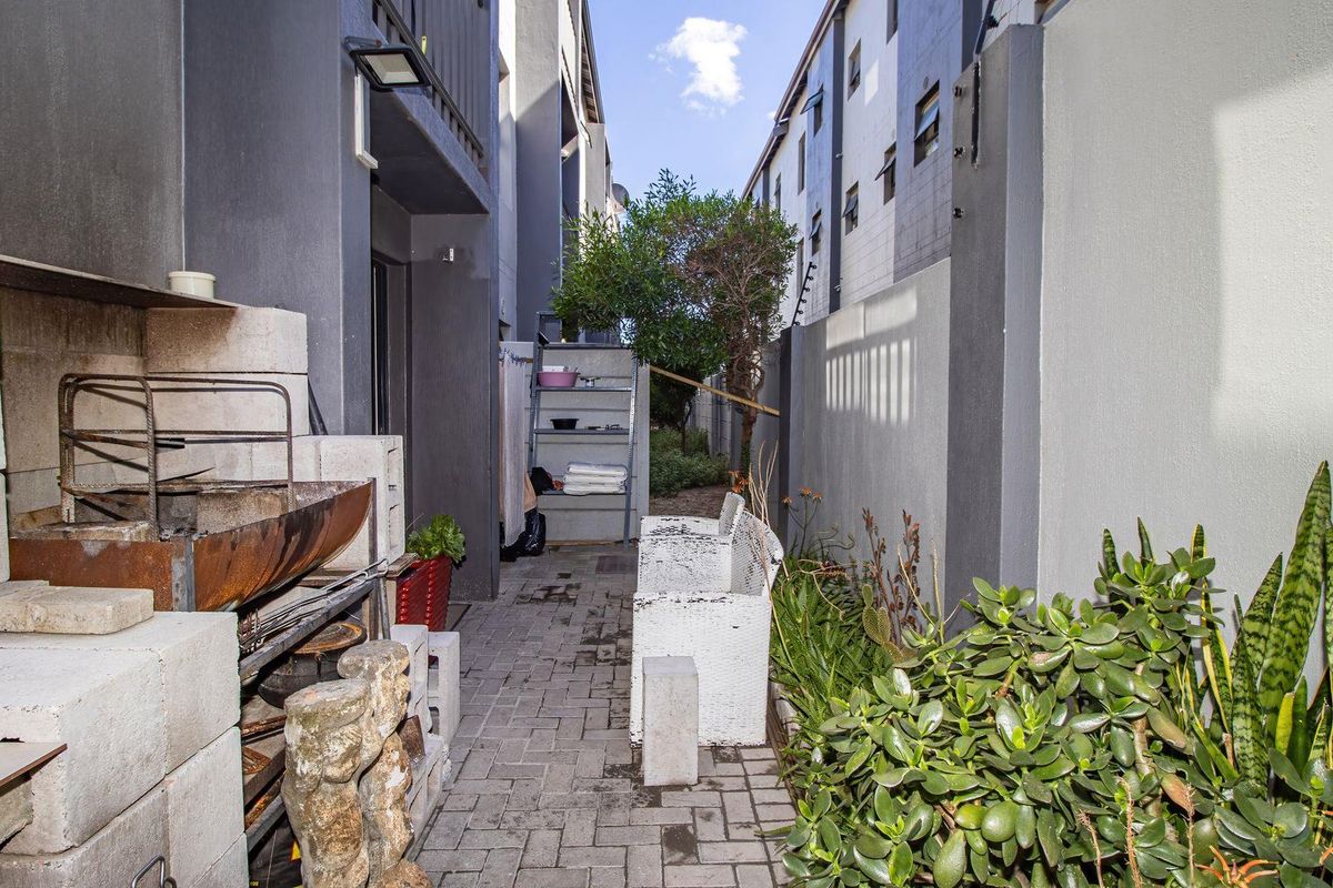 A narrow rear courtyard area featuring paved flooring, perimeter boundary walls, and a built-in masonry braai structure.
