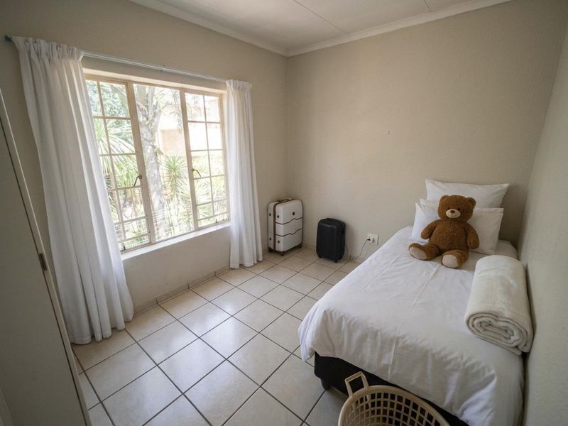 A simple bedroom featuring tiled flooring and a large window that allows for natural light.