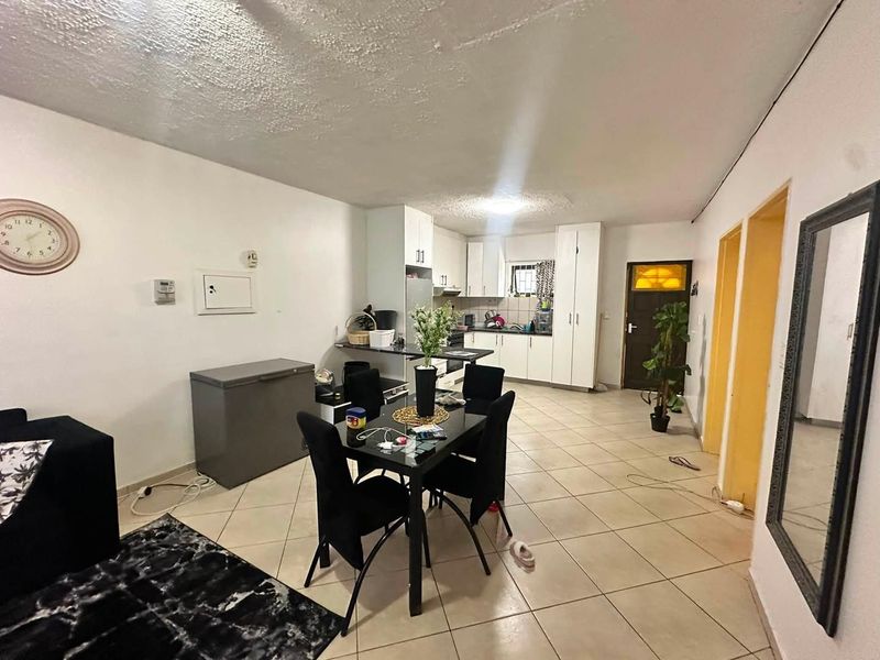 Open-plan living and kitchen area featuring tiled flooring, built-in cabinetry, and a functional layout suitable for modern updates.