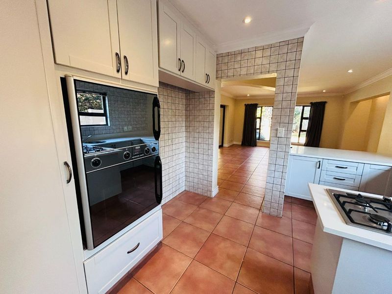 A functional kitchen featuring built-in cabinetry, a gas hob, and an integrated oven, flowing into an open-plan living area with tiled flooring throughout.