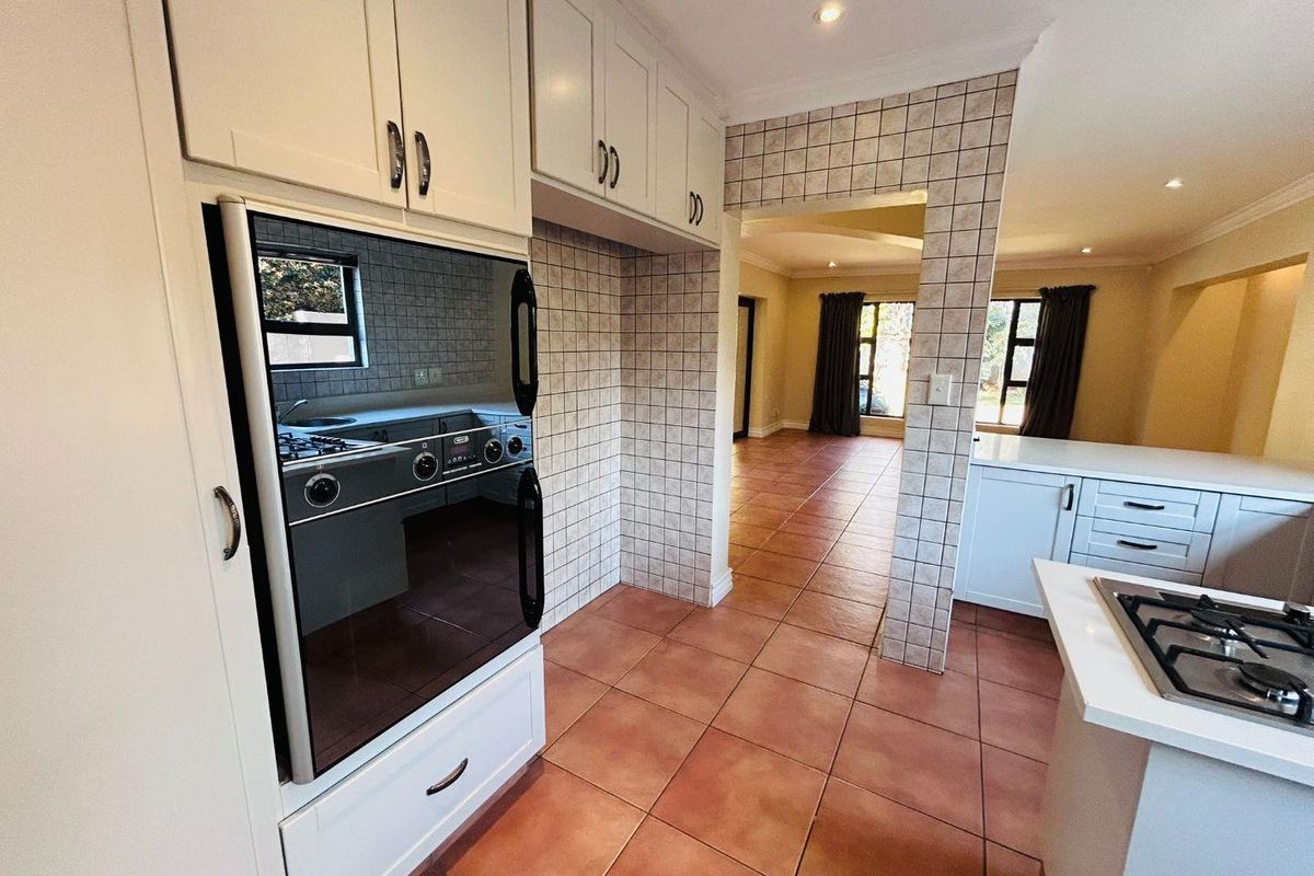 A functional kitchen featuring built-in cabinetry, a gas hob, and an integrated oven, flowing into an open-plan living area with tiled flooring throughout.