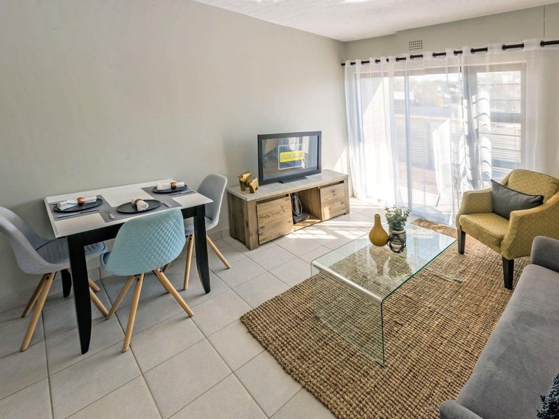 Bright open-plan living and dining area featuring neutral tiled flooring and large sliding glass doors providing access to the outdoor space.