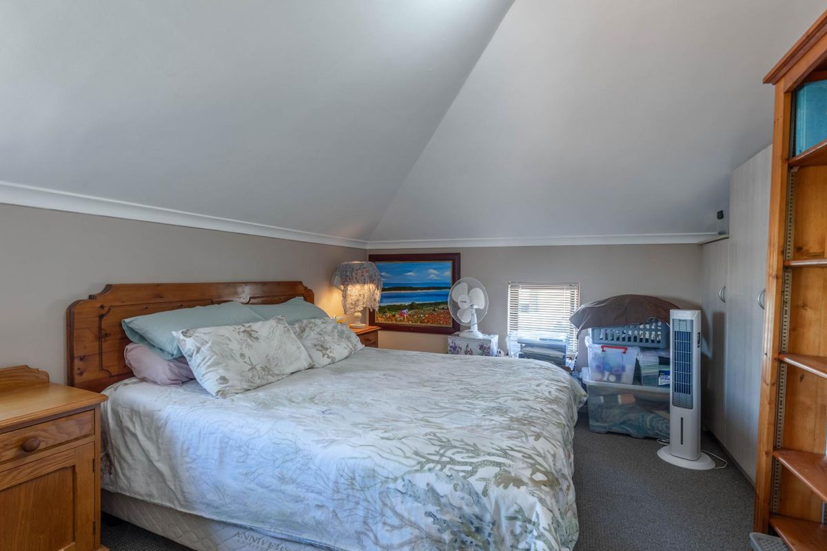 A bedroom featuring a sloped ceiling, carpeted flooring, and built-in storage cabinetry.