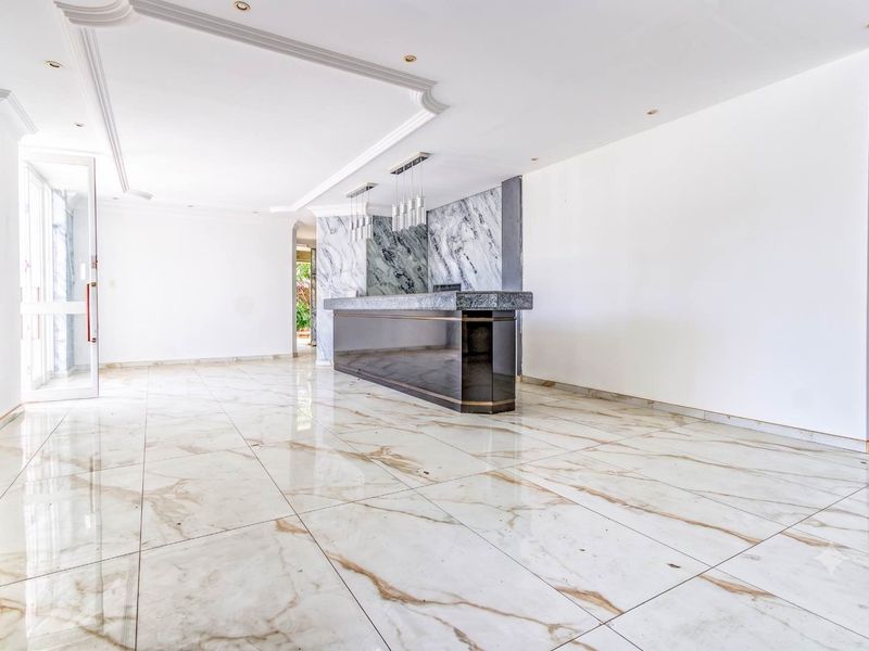 Spacious office area featuring polished marble flooring, a built-in reception desk with marble accents, and elegant recessed ceiling detailing.