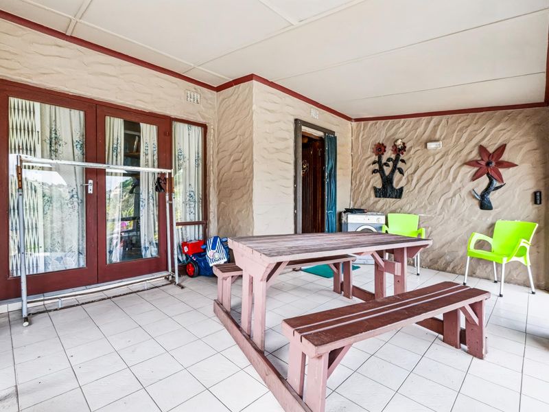 A covered patio area featuring tiled flooring, textured walls, and double glass door access to the interior living space.