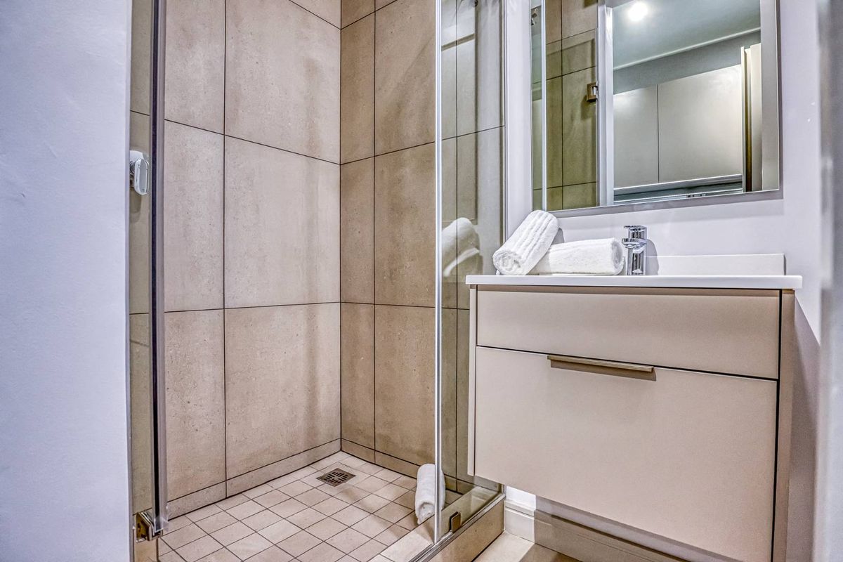 Modern bathroom featuring a glass-enclosed shower with large format wall tiles and a wall-mounted vanity unit with a basin.