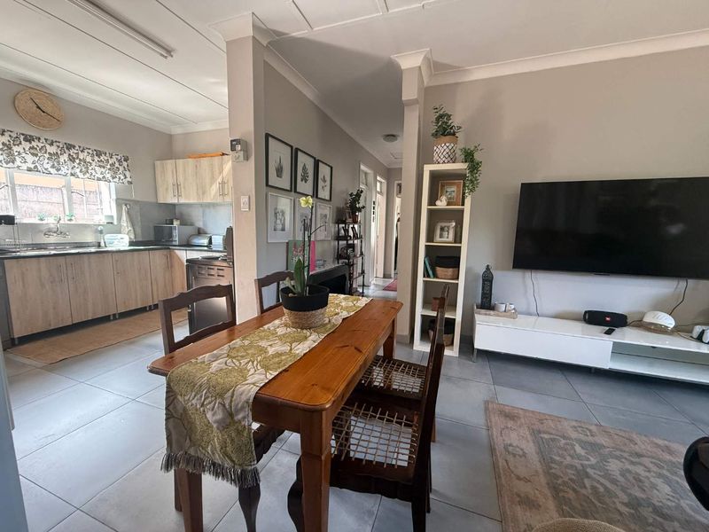 Open-plan living and dining area featuring tiled flooring, coved ceilings, and a functional kitchen with built-in cabinetry.