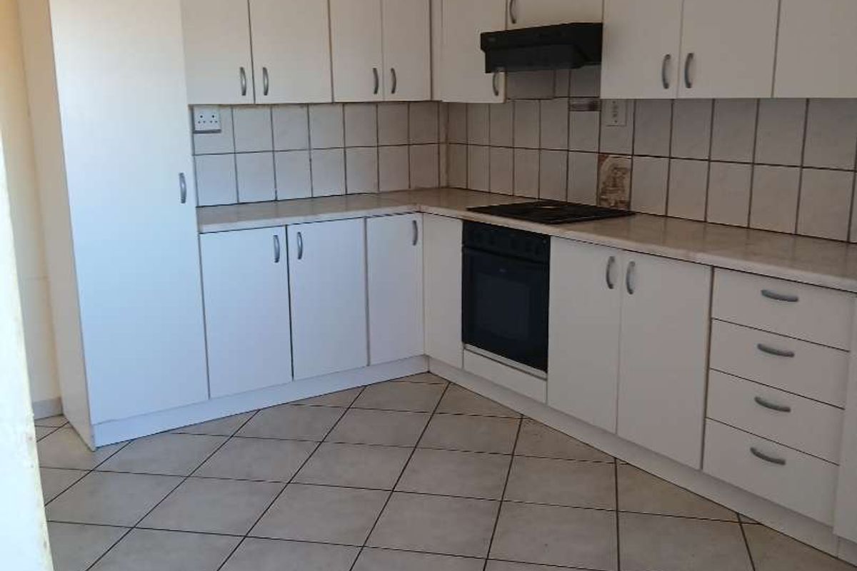 A functional kitchen featuring white cabinetry, tiled backsplash, built-in oven, hob, and extractor fan, complemented by tiled flooring.