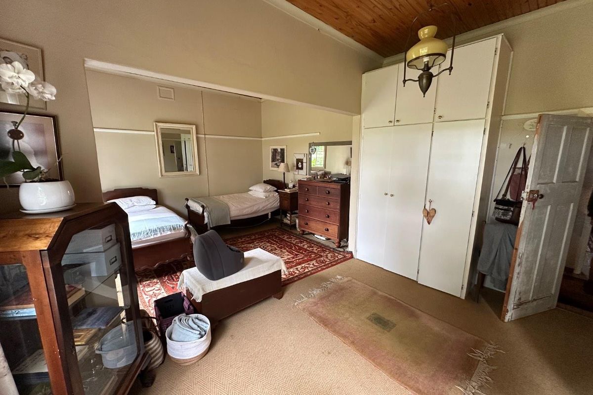Spacious bedroom featuring built-in cupboards, a warm timber ceiling, and classic picture rails, offering a comfortable and traditional living space.