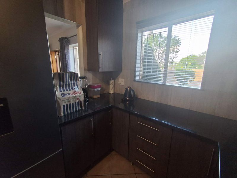 A functional kitchen featuring dark wood cabinetry, granite countertops, and tiled flooring, providing a clean and practical workspace.